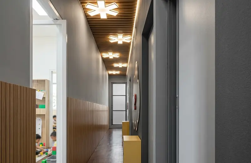Lorong kelas dengan lampu berbentuk bintang dan anak bermain balok